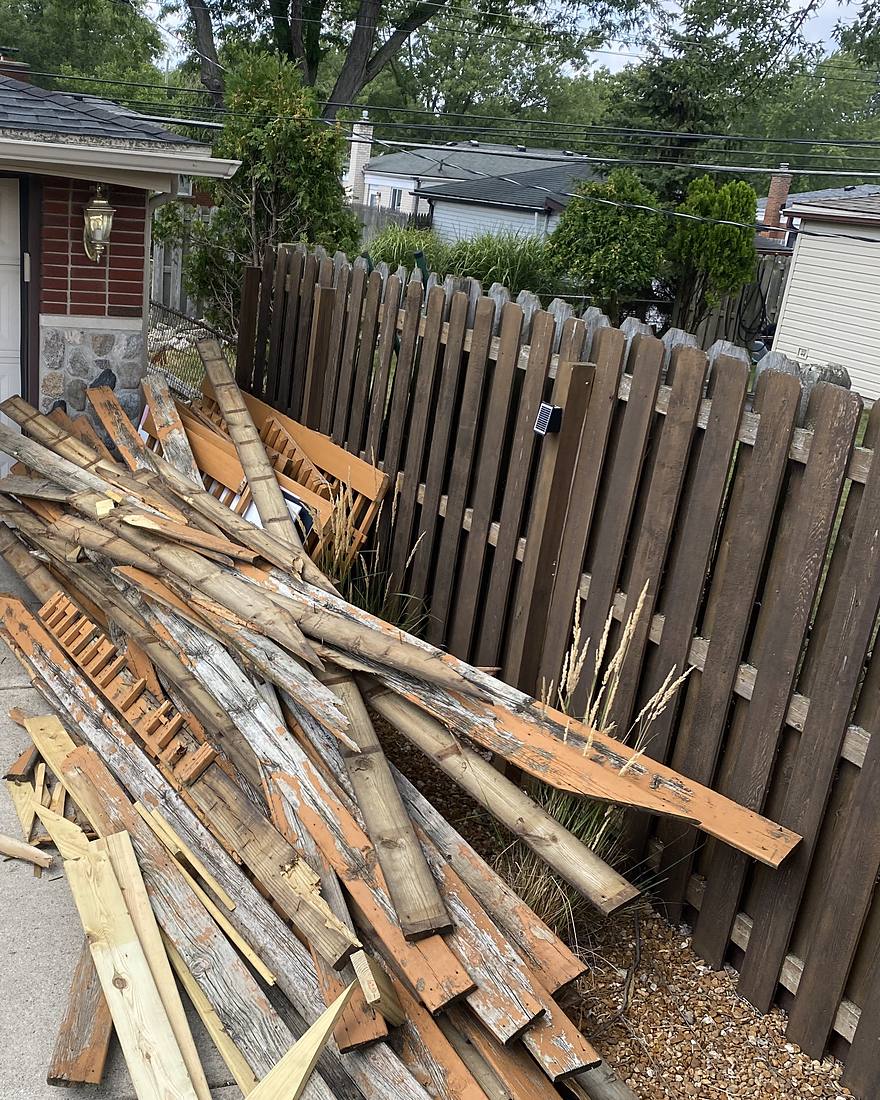 A driveway stacked with old deck boards and railings before removal